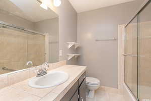 Full bathroom with tile patterned flooring, vanity, toilet, and shower / bath combination with glass door