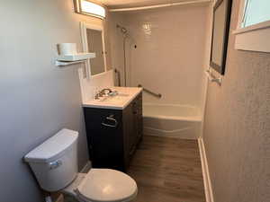 Full bathroom featuring toilet, vanity, shower / bath combination, and hardwood / wood-style flooring