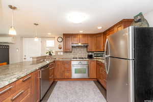 Kitchen featuring a wall mounted air conditioner, sink, light wood-type flooring, appliances with stainless steel finishes, and decorative light fixtures