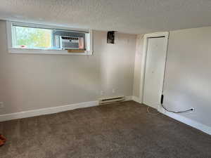 Interior space with carpet floors, a textured ceiling, and a baseboard radiator