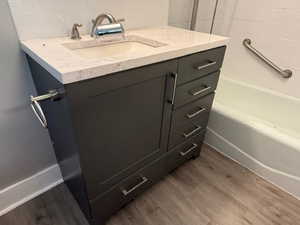 Bathroom featuring hardwood / wood-style flooring, vanity, and decorative backsplash