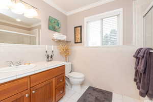 Bathroom featuring vanity, tile patterned floors, toilet, ornamental molding, and tile walls