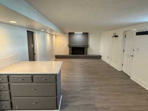 Unfurnished living room featuring a textured ceiling, dark hardwood / wood-style floors, and a stone fireplace