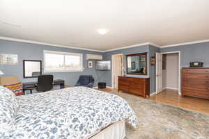 Bedroom featuring wood-type flooring, a wall unit AC, and ornamental molding