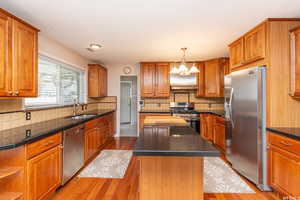 Kitchen featuring backsplash, sink, light wood-type flooring, a kitchen island, and stainless steel appliances