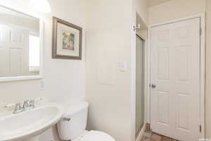 Bathroom featuring toilet, a shower with shower door, and sink