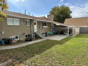 Rear view of house with central AC, a patio area, and a lawn