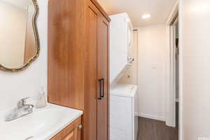 Bathroom with hardwood / wood-style floors, vanity, and stacked washer and dryer