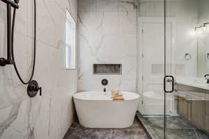 Bathroom featuring vanity, independent shower and bath, and tile walls