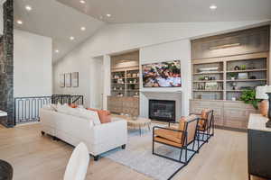 Living room with built in shelves, high vaulted ceiling, and light hardwood / wood-style floors