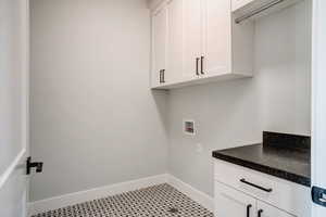 Washroom featuring cabinets, hookup for a washing machine, and light tile patterned floors