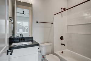 Full bathroom with vanity, toilet, ceiling fan, and  shower combination