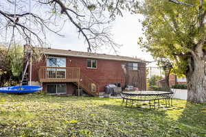 Rear view of house with a trampoline, a yard, and central air condition unit