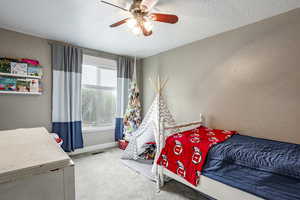 Bedroom featuring carpet flooring, ceiling fan, and a textured ceiling