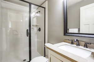 Bathroom with vanity, toilet, and a shower with door