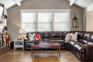 Living room with vaulted ceiling with beams and dark hardwood / wood-style flooring