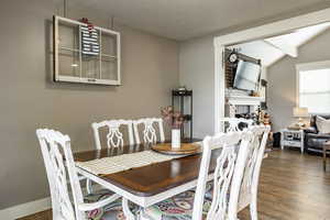 Dining room featuring hardwood / wood-style flooring, a textured ceiling, and vaulted ceiling