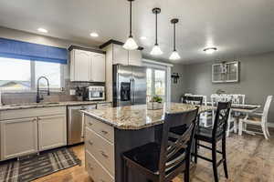 Kitchen featuring stainless steel appliances, hanging light fixtures, a healthy amount of sunlight, and sink