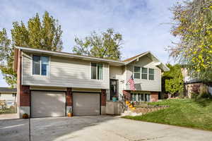 Raised ranch featuring a garage and a front yard