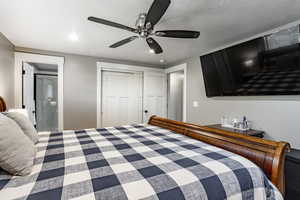 Bedroom featuring ceiling fan, ensuite bathroom, a textured ceiling, and a closet