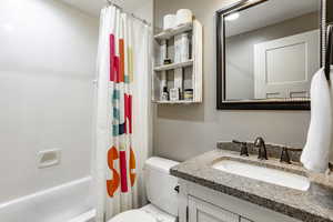 Full bathroom with vanity, toilet, and shower / bath combo with shower curtain