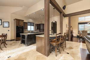 Kitchen with a center island, tasteful backsplash, light stone counters, a breakfast bar area, and dark brown cabinets