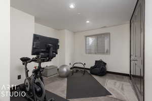 Workout room with light colored carpet and a textured ceiling