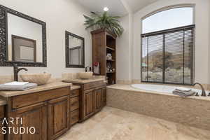 Bathroom featuring tile patterned floors, vanity, and tiled bath