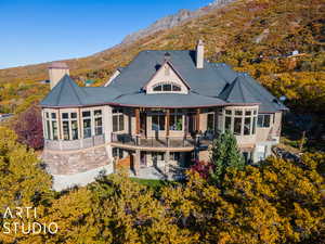 Rear view of house with a sunroom, a mountain view, a balcony, and a patio