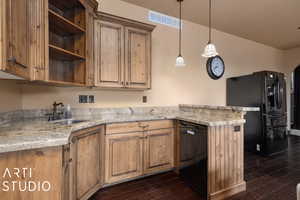 Kitchen featuring sink, light stone counters, dark wood-type flooring, and black appliances