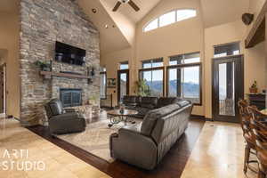 Living room with high vaulted ceiling, ceiling fan, and a stone fireplace