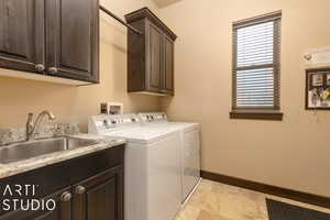 Laundry room featuring washing machine and dryer, sink, and cabinets