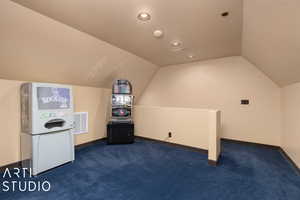 Bonus room featuring dark colored carpet, lofted ceiling, and a textured ceiling