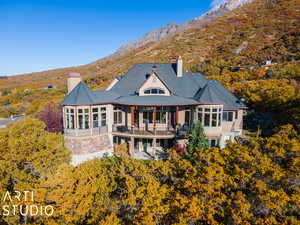 Rear view of house featuring a mountain view, a balcony, and a sunroom