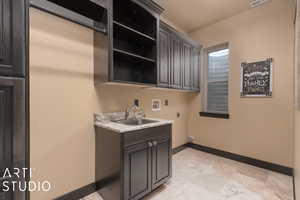 Washroom with hookup for a washing machine, sink, cabinets, and hookup for an electric dryer