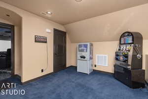 Bonus room with dark carpet and vaulted ceiling