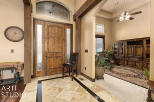 Foyer entrance featuring ceiling fan and a towering ceiling