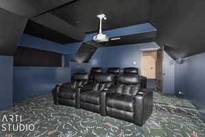 Carpeted home theater room featuring vaulted ceiling