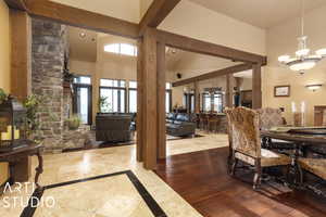 Dining area featuring an inviting chandelier, high vaulted ceiling, light hardwood / wood-style flooring, and ornate columns