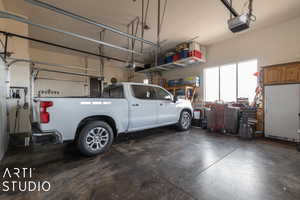 Garage featuring white refrigerator and a garage door opener