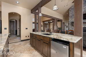 Kitchen with sink, hanging light fixtures, vaulted ceiling, light stone countertops, and stainless steel appliances