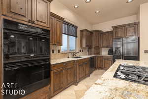 Kitchen featuring sink, backsplash, light stone countertops, and black appliances