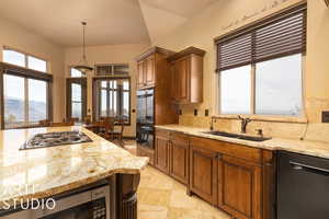 Kitchen with decorative backsplash, light stone countertops, sink, black appliances, and a mountain view