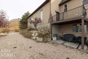 Back of house featuring a mountain view, a balcony, and a patio