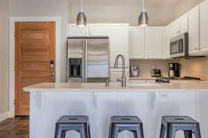 Kitchen featuring white cabinets, pendant lighting, a breakfast bar area, and appliances with stainless steel finishes