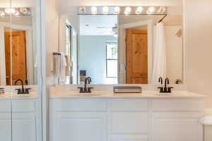 Bathroom featuring curtained shower, vanity, and ceiling fan