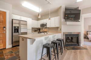 Kitchen featuring kitchen peninsula, pendant lighting, a breakfast bar, white cabinets, and appliances with stainless steel finishes