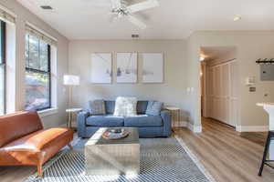 Living room featuring light wood-type flooring, electric panel, and ceiling fan