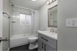 Full bathroom with toilet, vanity, tile patterned floors, and shower / bathtub combination with curtain