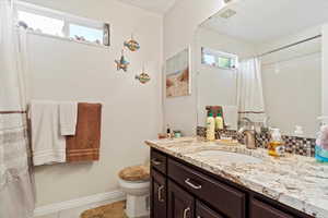 Bathroom with tile patterned flooring, vanity, a healthy amount of sunlight, and toilet